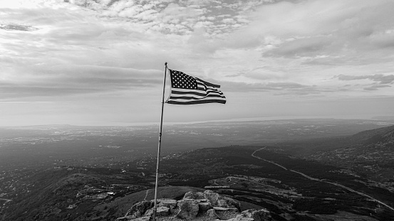 A grayscale shot of USA flag waving on the hilltop