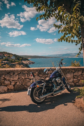 Vrbnik, Croatia – August 16, 2022: A Harley Davidson motorcycle parked on a beautiful viewpoint in Croatia overlooking the sea