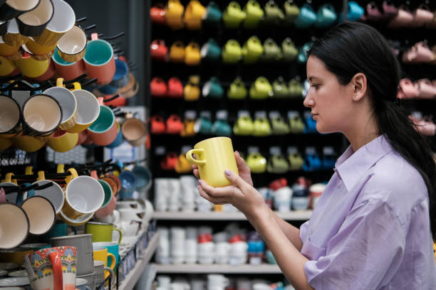 istock Young woman customer choosing ceramic cups in modern tableware shop. Home decor and comfort concept 1453929009