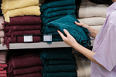 Close up of woman hands shopping at textile department and holding towel at home goods store. Home decor and comfort concept