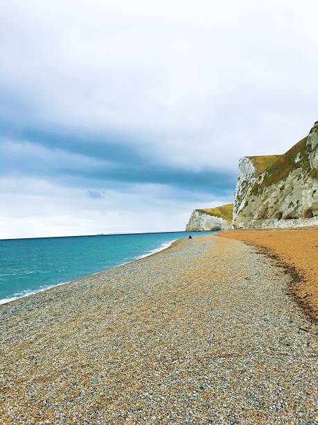 istock Calm scene with low tides at the shore under tall cliffs and the cloudy sky 1453930944