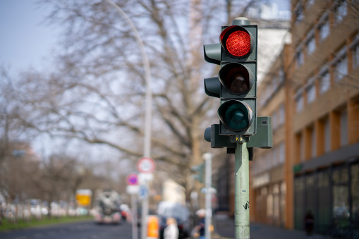 A photo of traffic lights in a city with the red lamp on