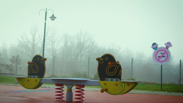 foggy, cold and empty playground, rocking seesaw on a foggy day