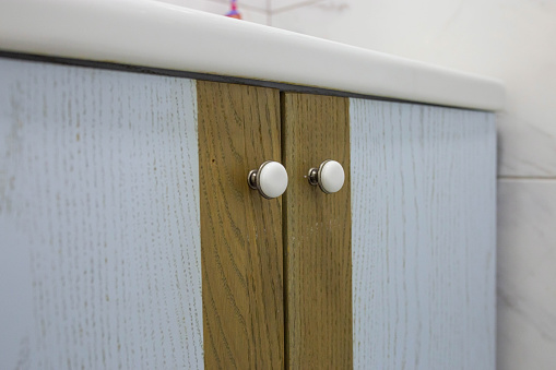 Close-up of two small round doorknobs on a bathroom cabinet.