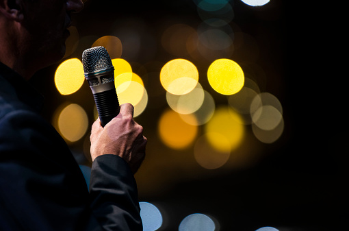 A singer holds a microphone during his concert with bokeh lights in the background
