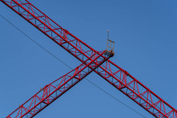 A low angle shot of a big, red construction crane against a blue sky