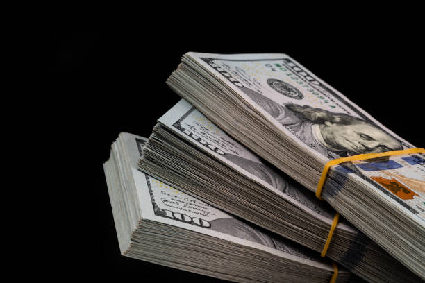 istock Three bundles of 100 american dollar bills on a black background 1453939112