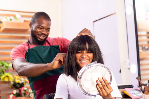 parrucchiere nero felice che lavora sui capelli di una giovane cliente in un salone - owner hair salon beauty spa female foto e immagini stock