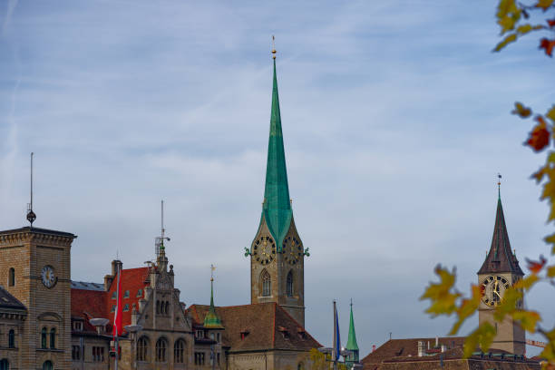 kirchturm der berühmten kirche frauenmünster und st. peter kirche in der mittelalterlichen altstadt von zürich an einem blau bewölkten herbsttag. - autumn clock roof colors stock-fotos und bilder