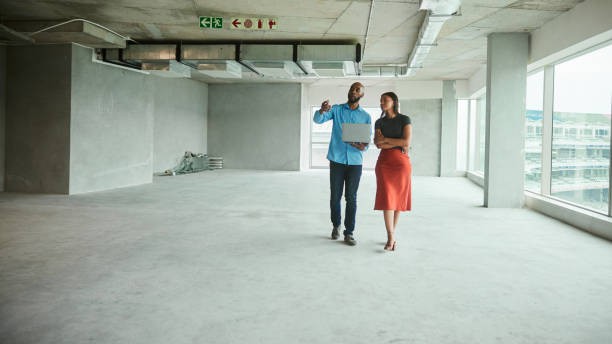 istock Architects discussing plans on a laptop while walking in an interior building site 1453946261