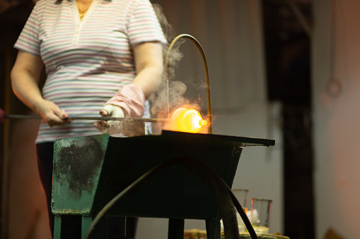 A glass blower is working on the manufacture of glass vases and glasses.Cooling of an incandescent product with water. Up to 20 workers can be involved simultaneously in the production of particularly complex products.