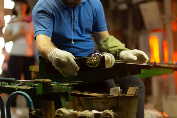 a glass blower is working on the manufacture of glass vases and glasses. - glass factory imagens e fotografias de stock