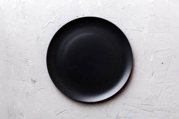 istock Top view of black plate on cement background. Empty space for your design 1453949769