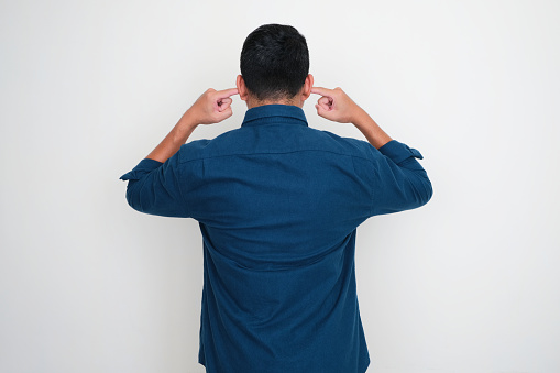 Back view of Adult man closing his ears with fingers