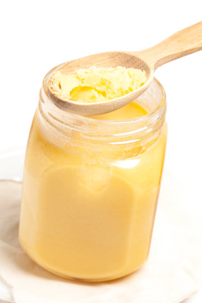 istock Ghee in jar and wooden spoon isolated on white background. 1453954433