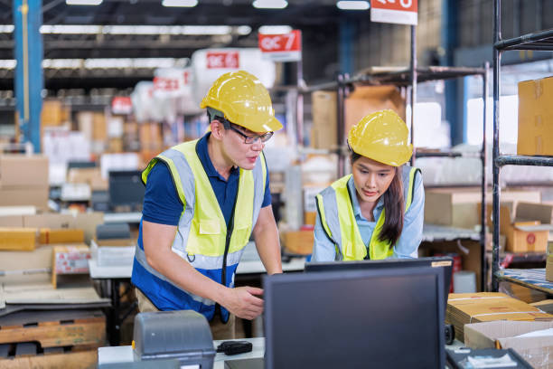 istock Staff working in large depot storage warehouse trainee check packing box and scan at cashier counter 1453957417