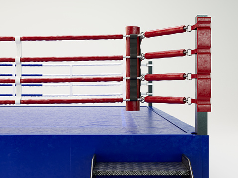 A modern regulation sized boxing ring with opposing blue and red corners on an isolated white studio background - 3D render