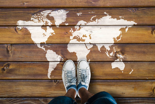 World map on a wooden floor and man in shoes stock photo