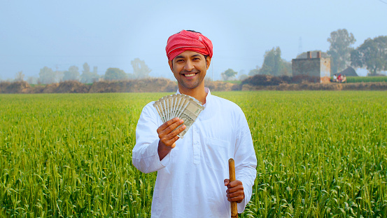 Handsome agricultural laborer in white kurta pajama holding five hundred rupees banknotes - financial concept