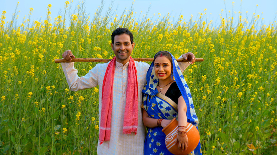 Medium shot of an Indian traditional married couple smiling cheerfully at each other - farmer's family