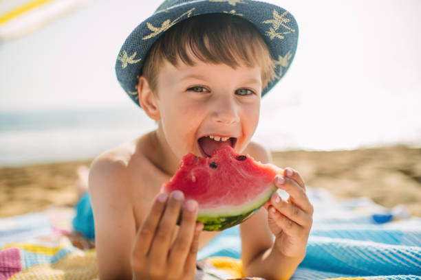 istock Happy child eating watermelon on beach vacations 1453962829