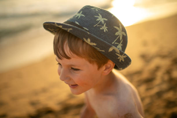 Beach accessories for sun protection: children's yellow straw hat, pink heart-shaped glasses on a white background. Layout with space for text. Ready for travel and beach holidays at sea