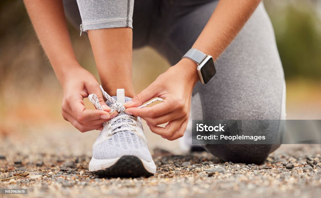 Shoes, fitness and exercise with a sports woman tying her laces before training, running or a workout. Hands, health and cardio with a female runner or athlete getting ready for an endurance run Running Stock Photo