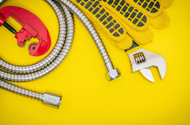 istock Plumbing tools and gloves for connecting water hoses on yellow desktop 1453963748