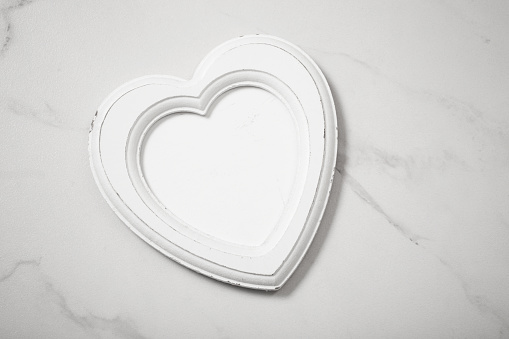 wooden frame in form heart on white marble background