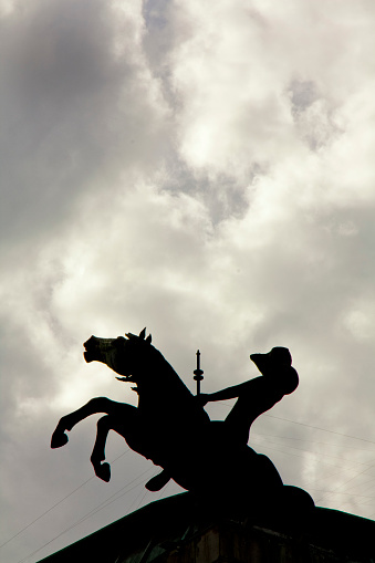 Vigo, Spain - June 4, 2011: Horse and man statue outlined, located on top of García Barbón theatre building, overcast sky. Vigo, Galicia, Spain.