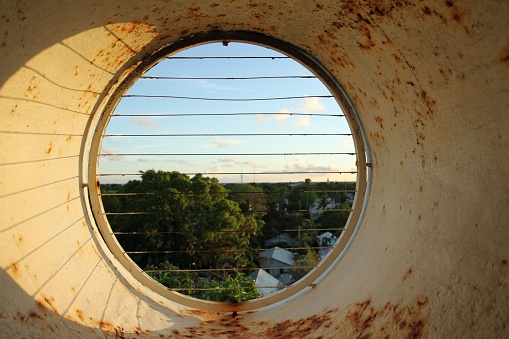 A round rusty fenced window to the green park