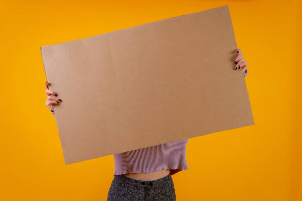 istock A cardboard sign held by a woman's hands on a yellow background 1453966933