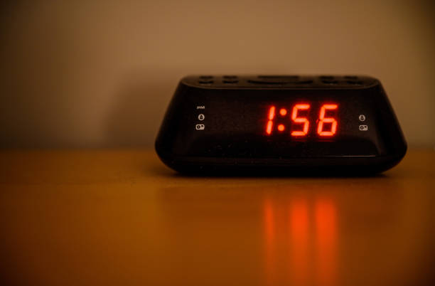 Digital radio alarm clock on a table at night stock photo