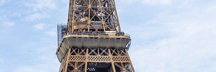 Second floor of the Eiffel Tower on sunny day with protective nets and tourists on the balconies in Paris, France