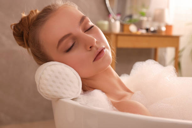 istock Young woman using pillow while enjoying bubble bath indoors 1453969492