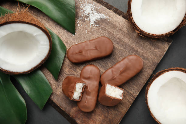 istock Delicious milk chocolate candy bars with coconut filling on black table, flat lay 1453969595