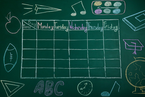 Weekly school timetable drawn on green chalkboard