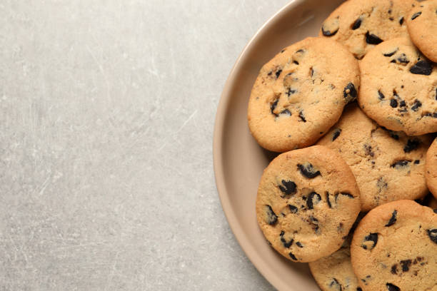 istock Plate with delicious chocolate chip cookies on grey table, top view. Space for text 1453970148