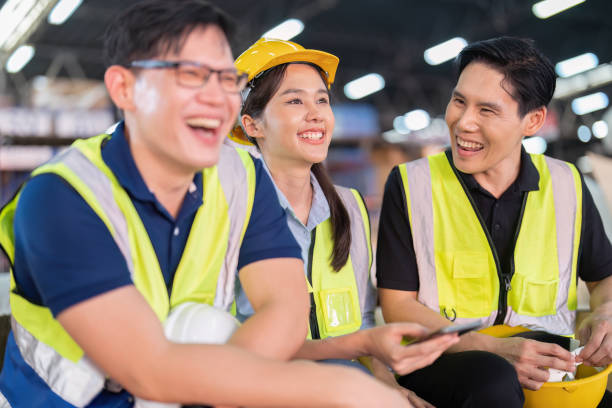 istock Staff in large storage warehouse together sit back relax funny laughing check mobile phone 1453970341