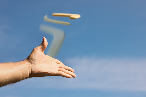 Man throwing boomerang against blue sky, closeup