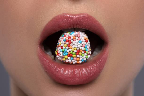 istock Woman with beautiful lips eating candy on grey background, closeup 1453971946
