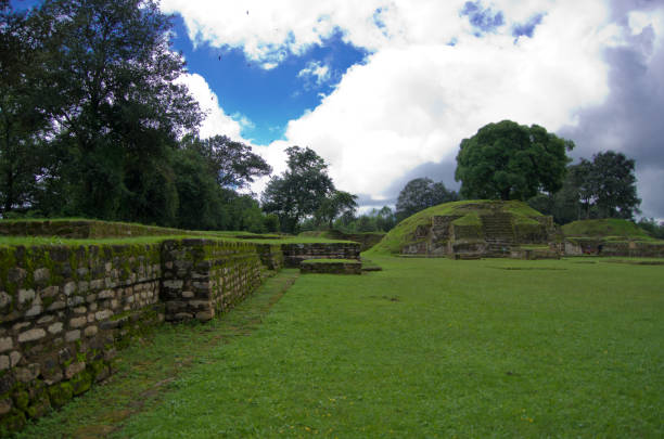 hermosa toma de paisaje del parque iximché con campos y árboles con cielo azul en guatemala - iximche fotografías e imágenes de stock