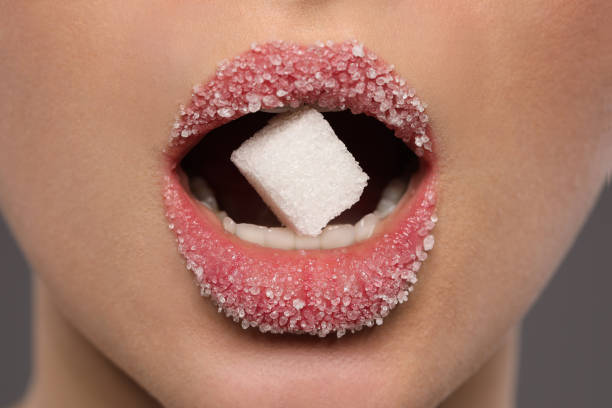 istock Woman with beautiful lips eating sugar cube on grey background, closeup 1453973904