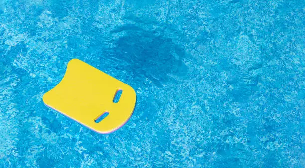 Safe pool training aid float foam board tool. Pink Swimming kickboard on blue water surface of swim pool. Mockup, Panoramic banner, copy space for text or design. Water sport, active lifestyle