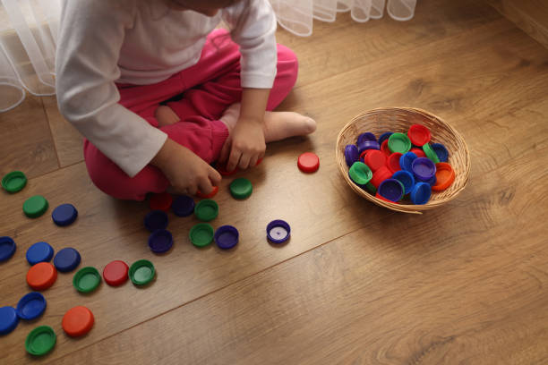 istock Little girl playing plastic bottle caps 1453974260