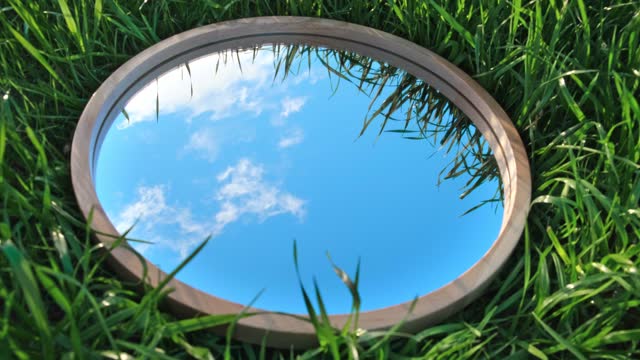 Cloudy Blue Sky Reflection in Round Wood Mirror on Summer Field with Green Grass. Nature Concept. Earth Day. Save Environment. Peace. Ecology Protection. Climate Change, Global Warming Effect Problem