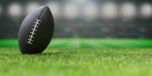 istock American football ball on a lush green grassy field, Super bowl,  3d render 1453983473