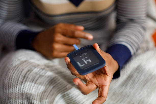 une jeune femme vérifie son taux de glucose à la maison - blood sugar test examining instrument of measurement diabetes photos et images de collection