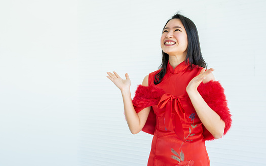 Asian beautiful woman wearing red dress or qipao, smiling with happiness, celebrate Chinese New year, standing on white background with copy space