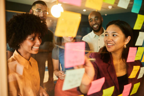 istock Diverse businesspeople smiling during a brainstorming session with adhesive notes 1453986861